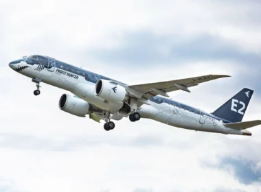 Commercial airplane in flight with 'Profit Hunter' livery, engines under wings, landing gear extended, tail marked E2.