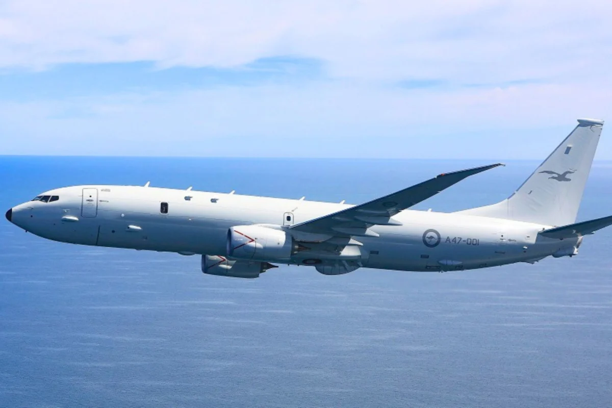 Military transport aircraft flying over the ocean viewed from the side with wings and tall tail visible