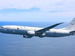 Military transport aircraft flying over the ocean viewed from the side with wings and tall tail visible