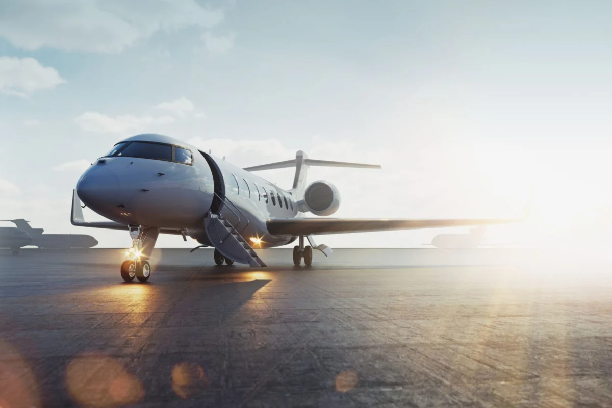 Private jet parked on a sunlit airport tarmac with boarding stairs attached to the door and jet engines visible to the side