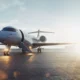 Private jet parked on a sunlit airport tarmac with boarding stairs attached to the door and jet engines visible to the side