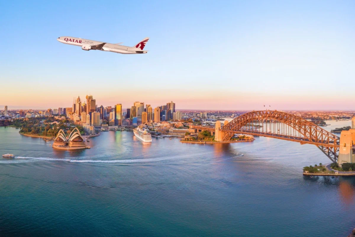 Qatar Airways adds Western Sydney as winter network broadens Airplane soaring above Sydney harbor with the Opera House and Harbour Bridge at sunset Qatar plane visible