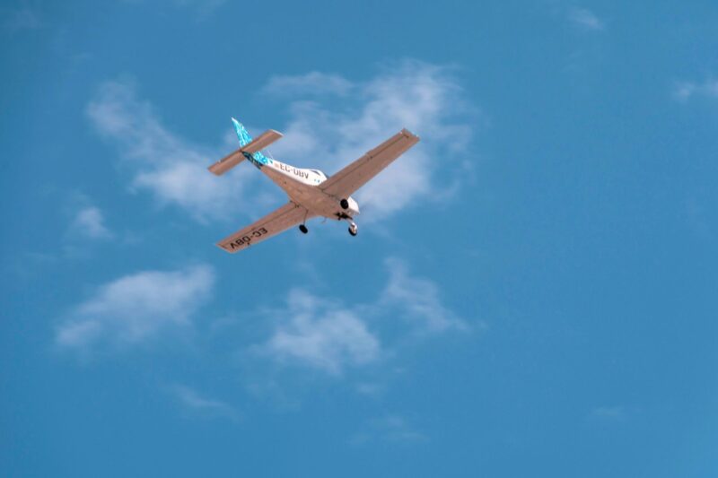Small single engine airplane in midflight against a clear blue sky registration EC UBV visible on the fuselagewing