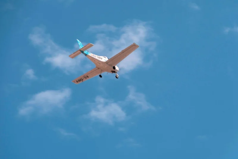 Small single engine airplane in midflight against a clear blue sky registration EC UBV visible on the fuselagewing