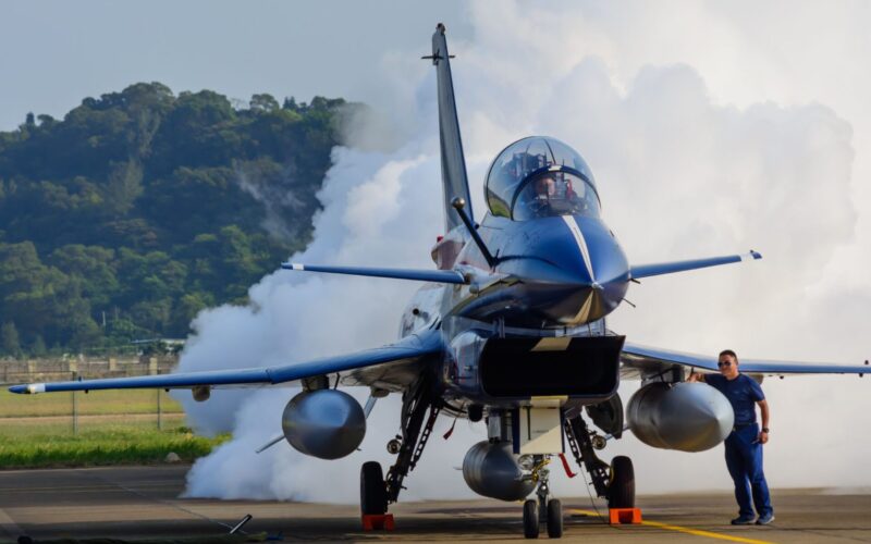 Indonesia to get first Chinese J 10s in 6 months reports Blue fighter jet on runway with smoke behind it and a ground crew member in blue standing beside the aircraft cockpit canopy visible and orange chocks at the nose gear