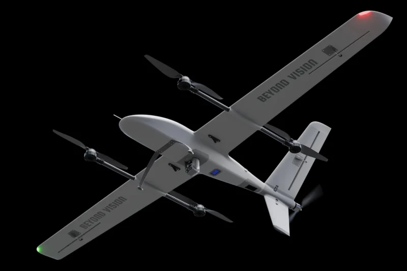 Gray fixed wing drone with four propellers and BEYOND VISION on the wings against a black background