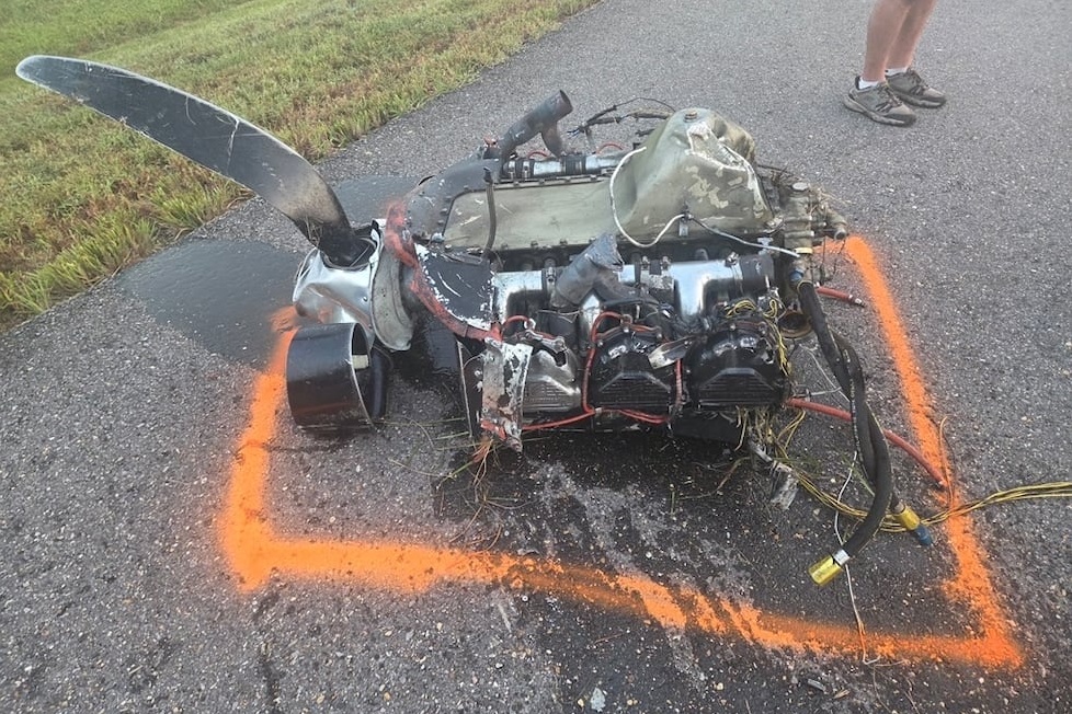 cessna 210 engine Damaged small aircraft engine with a bent propeller on a paved road outlined in orange spray paint exposed wiring nearby