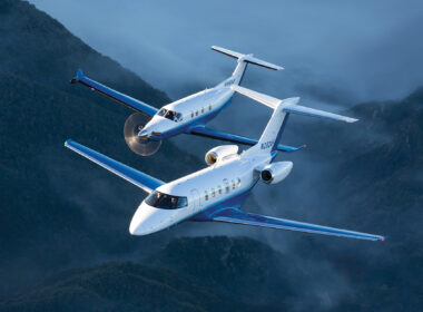download Two blue and white corporate jets fly in tight formation over misty green mountains
