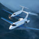Two blue and white corporate jets fly in tight formation over misty green mountains