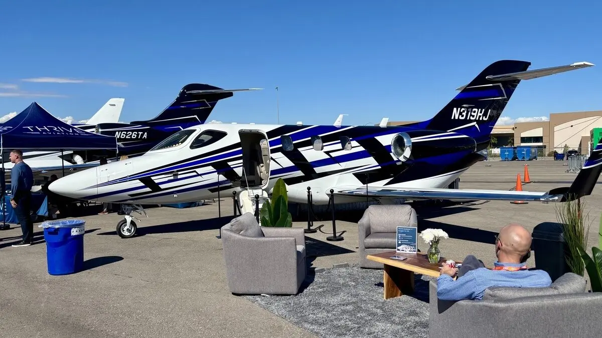 thrive hondajet 1200x675 Private jet on a tarmac with its door open set up for a lounge area with couches and a man relaxing nearby