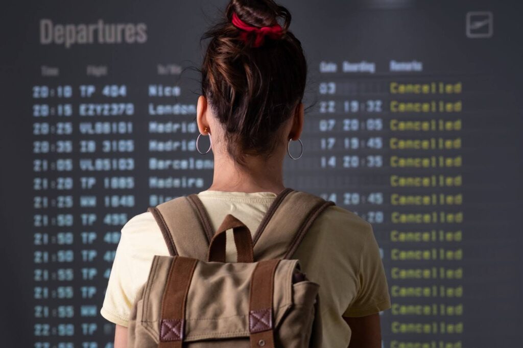 A woman looking at a departures screen with cancelled flights A woman looking at a departures screen with cancelled flights