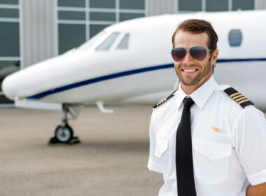 Confident pilot smiling in front of private jet