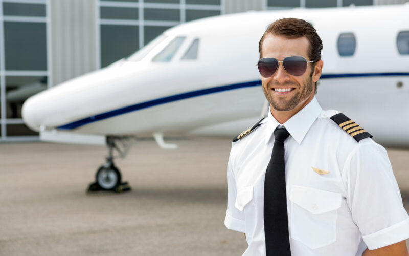 Confident pilot smiling in front of private jet