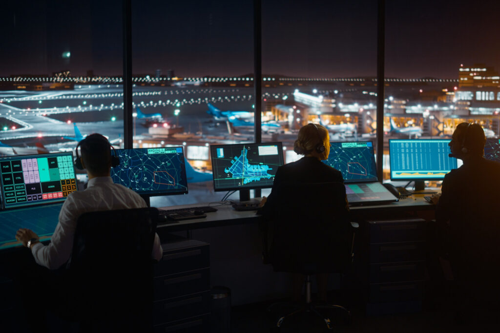 Diverse Air Traffic Control Team Working in Modern Airport Tower at Night