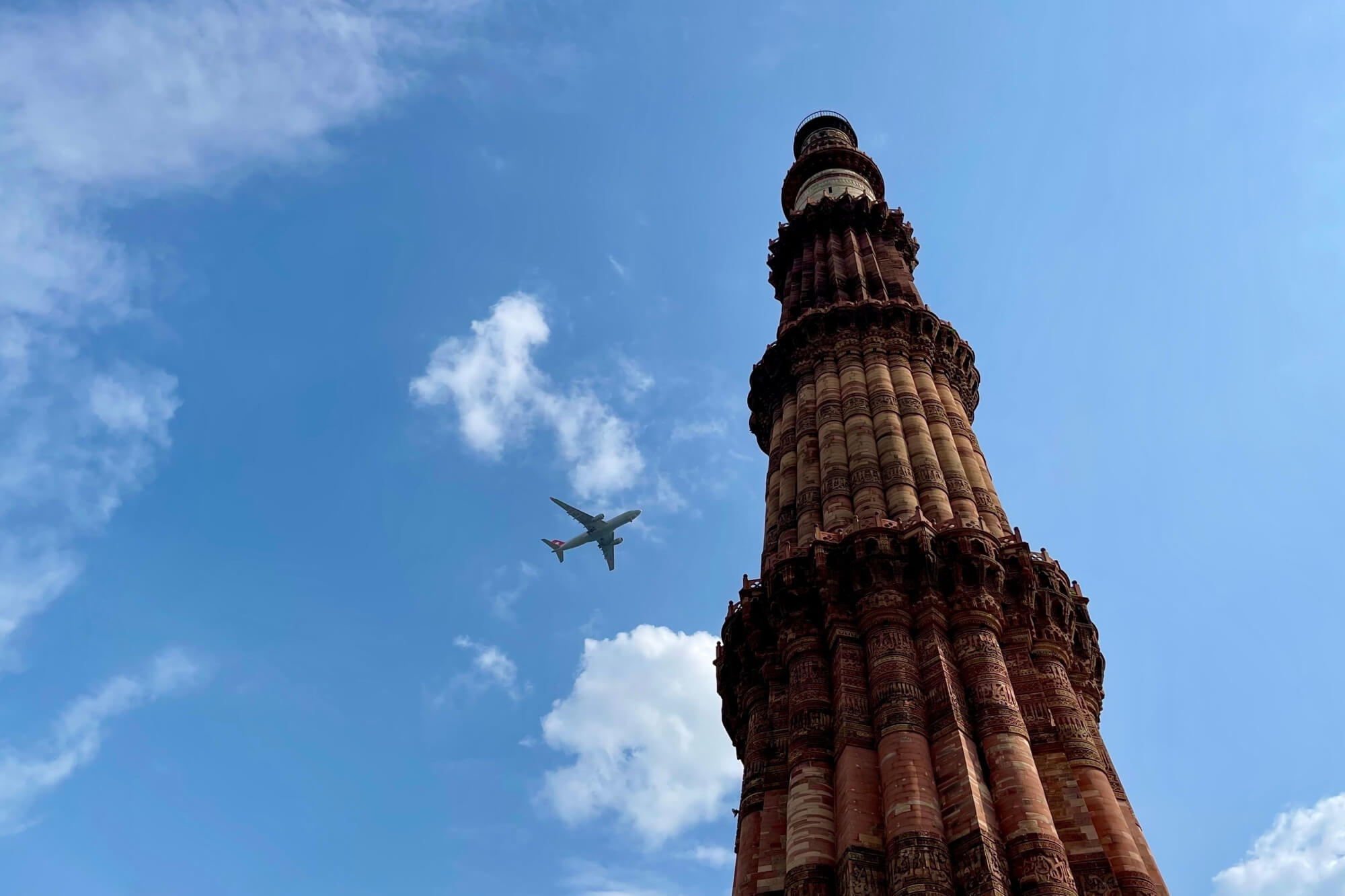 aircraft flies over Qutub Minar Tower, New Delhi, India
