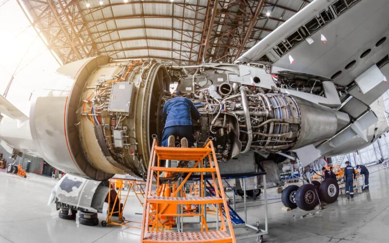Specialist mechanic repairs the maintenance of a large engine of a passenger aircraft in a hangar