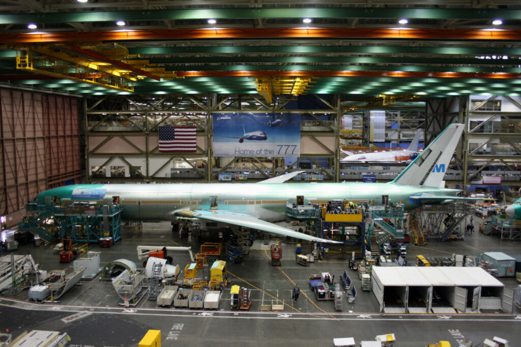 Unidentified Boeing employees continue work building a Boeing 777 jets at its Everett factory, including for KLM Royal Dutch Airlines with a Boeing 787 behind.