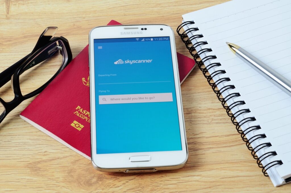 samsung phone on a table together with glasses, passport and notebook 