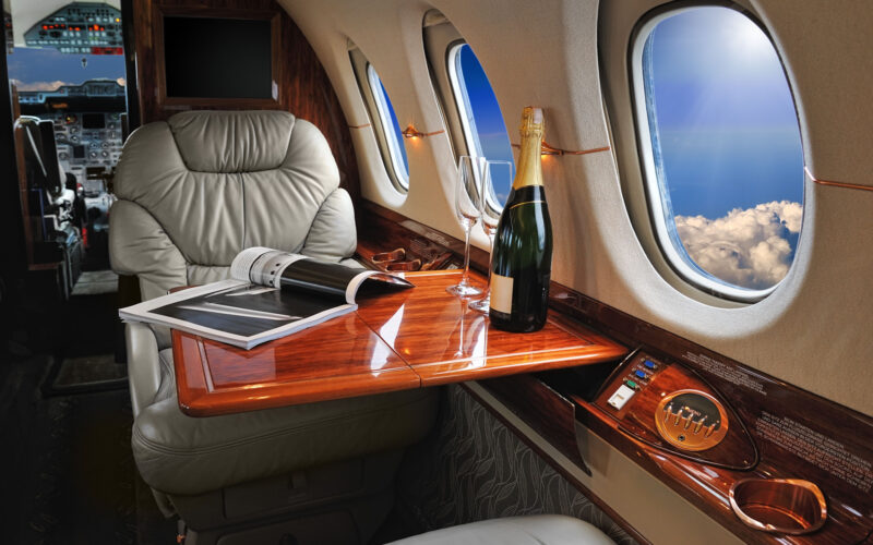 luxury interior in the modern business jet and sunlight at the window/sky and clouds through the porthole