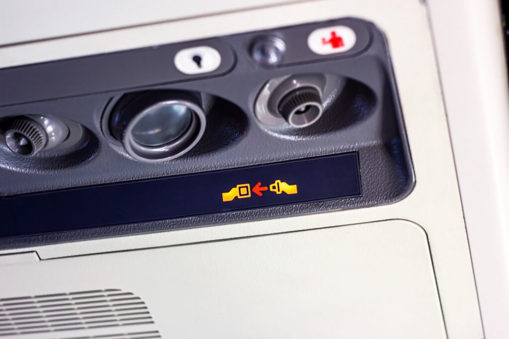 Attention announcement for passengers fasten your seat belt sign on information board inside the airplane cabin