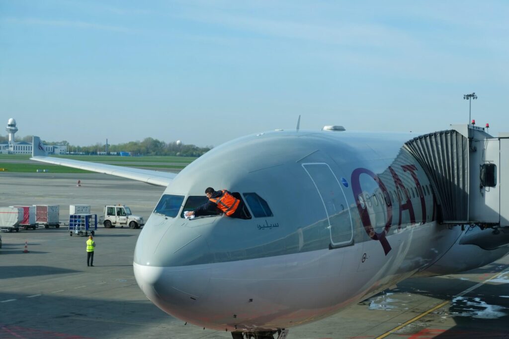 worker_is_cleaning_qatar_airways_plane_front_window_before_departure.jpg